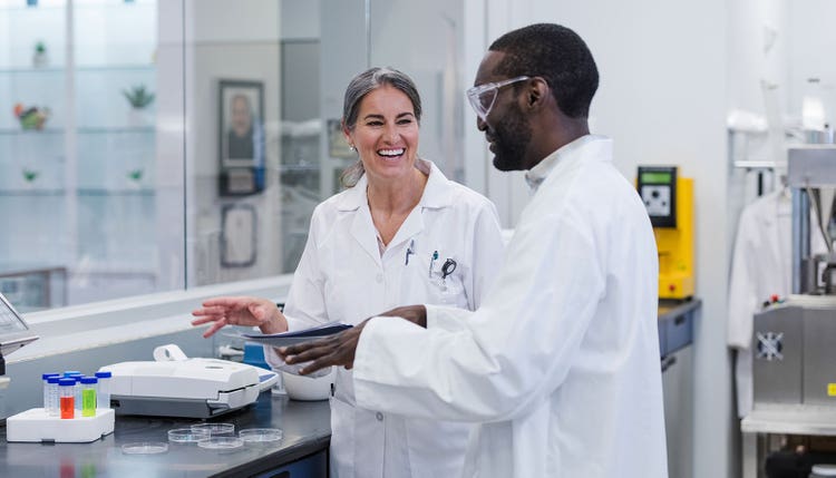Diverse coworkers enjoy conversation while working in laboratory