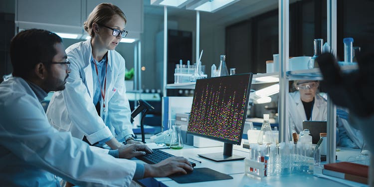 photograph of two researchers working in a lab looking at a computer display with genetic marker data.