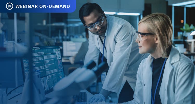 Webnar On-Demand: Two researchers in a lab discussing data on the computer display.
