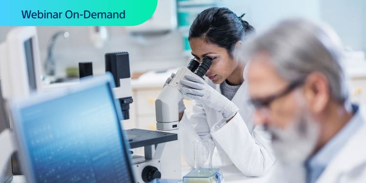 Webinar On-Demand. Photo of a busy lab with female researcher using microscope.