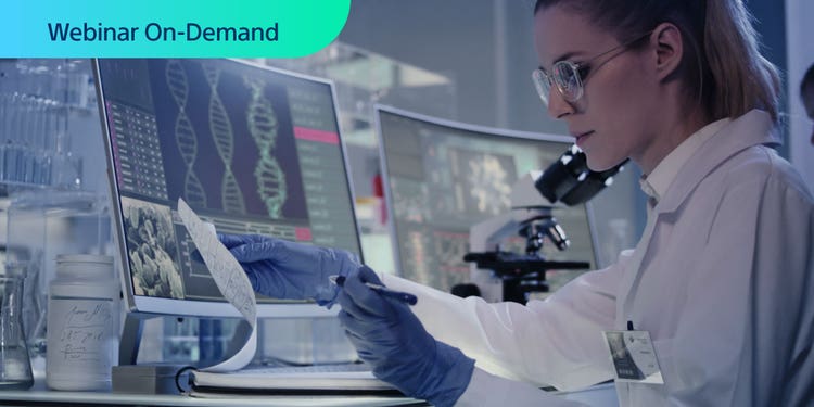 Webinar On-Demand. Photograph of researcher in a lab comparing data in a notebook to that on a computer display.