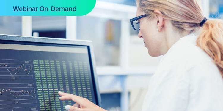 Webinar On-Demand. Photo of researcher in white coat analyzing data on a computer display.