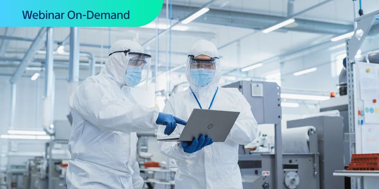 Webinar On-Demandt. Photo of two workers in cleansuits in a manufacturing facility are discussing the data on a laptop that one is holding.
