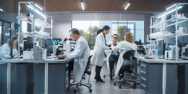 Photo of a busy research laboratory with five researchers all performing different tasks.