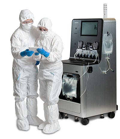 Two researchers looking at a mobile device standing in front of the CGX10 Cell Isolation System.