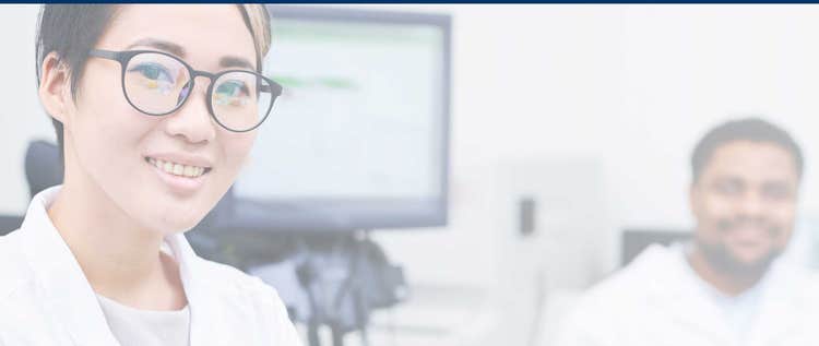 Researcher and colleague smiling in a lab setting.