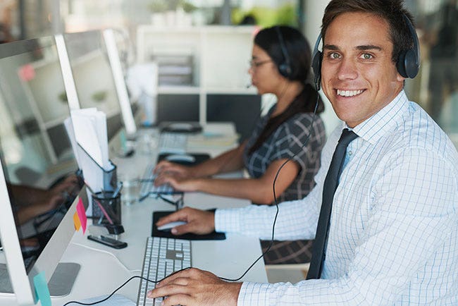 Customer service representative with headset at work with another colleague.
